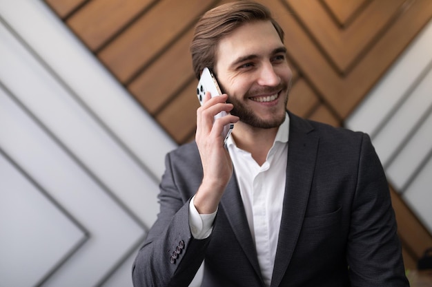 Hombre de negocios confiado en una chaqueta habla por teléfono en la oficina