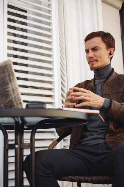 hombre de negocios confiado hablando durante una reunión en línea a través de una computadora portátil mientras trabaja a distancia en un café