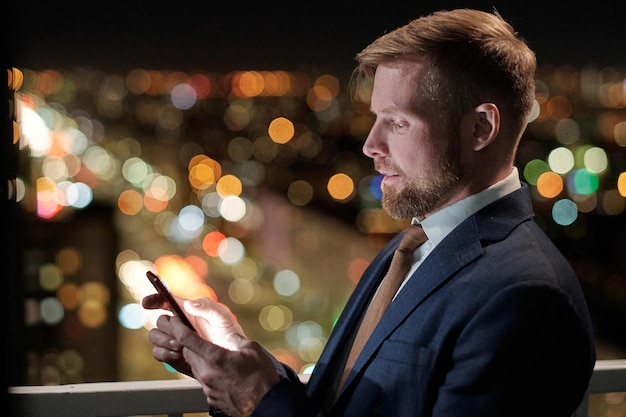 Hombre de negocios confiado que mira la pantalla del teléfono inteligente durante la comunicación