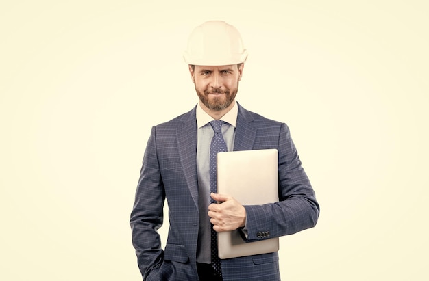 Hombre de negocios confiado en traje y casco de seguridad mantenga computadora aislada en ceo blanco