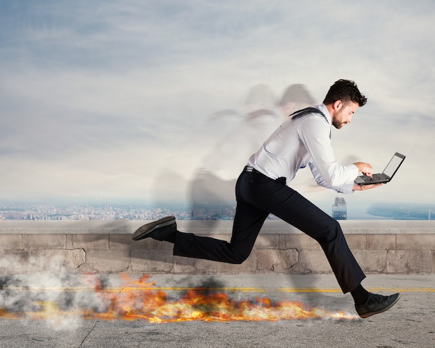 Foto el hombre de negocios corre rápidamente con el portátil dejando rastros de fuego. concepto de negocio rápido