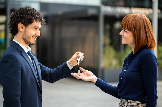 Un hombre de negocios le da las llaves de una nueva oficina a una mujer de negocios.