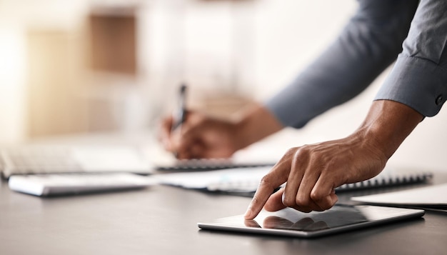 El hombre de negocios da la tableta y escribe notas planificando la agenda o el análisis en el escritorio de la oficina.