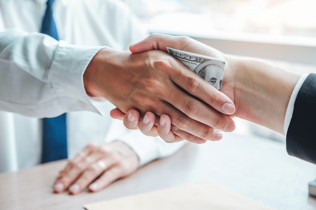 Hombre de negocios dándose la mano dando billetes de dólares al gerente comercial para hacer un contrato