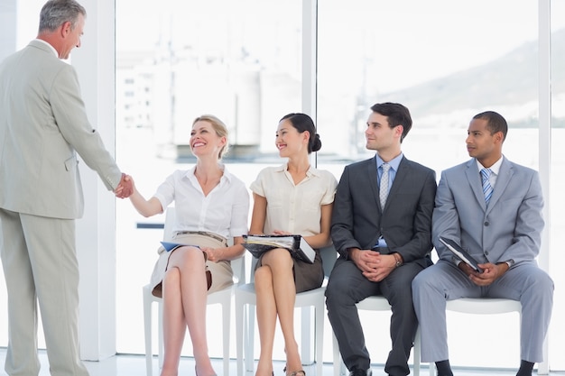 Hombre de negocios dándose la mano con la mujer por personas esperando la entrevista