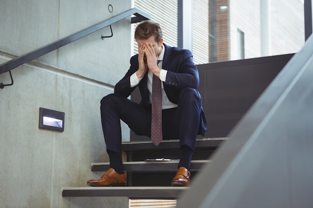 Foto hombre de negocios deprimido sentado en las escaleras