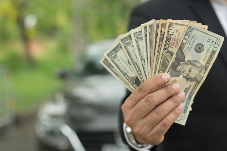 Foto hombre de negocios con dinero en la mano pararse delante del coche preparar el pago a plazos - concepto de seguro, préstamo y compra de coche