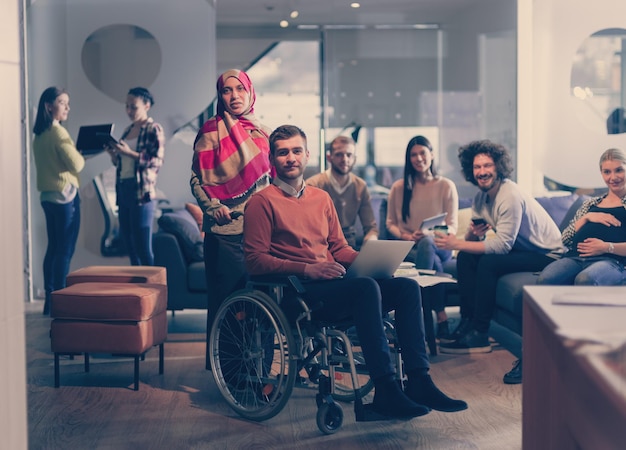 Hombre de negocios discapacitado en silla de ruedas en el trabajo en la oficina de coworking de espacio abierto moderno en la reunión del equipo