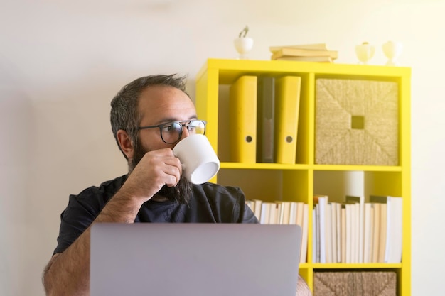 Hombre de negocios disfrutando de un café recién hecho. Trabajador de oficina trabajando en una laptop y bebiendo una bebida caliente.