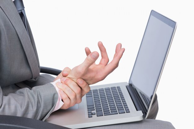 Hombre de negocios con dolor en la muñeca durante el uso de la computadora portátil