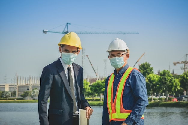 Hombre de negocios de dos personas hablando con senior en la construcción del sitio sobre proyecto de planta de bienes raíces y proyecto empresarial