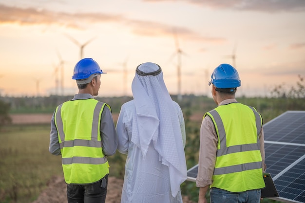 Hombre de negocios e ingeniero árabe inspecciona la construcción de paneles de células solares o células fotovoltaicas mediante dispositivo electrónico Energía renovable industrial de energía verde