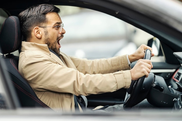 Un hombre de negocios elegante asustado está gritando y usando descansos en su auto