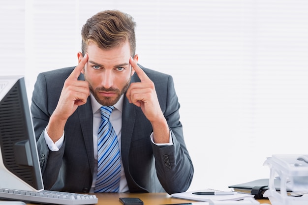 Hombre de negocios elegante con dolor de cabeza en el escritorio de oficina