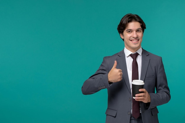 Hombre de negocios elegante lindo guapo en traje de oficina gris y corbata mostrando buena señal con café