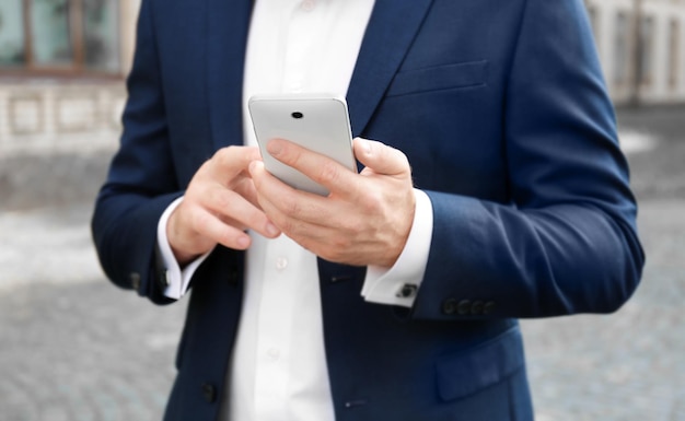 Hombre de negocios elegante que usa el teléfono móvil al aire libre