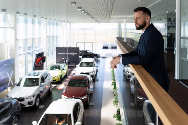 El hombre de negocios elige un nuevo automóvil de clase ejecutiva en un arrendamiento de automóviles conceptuales de la sala de exposición del concesionario