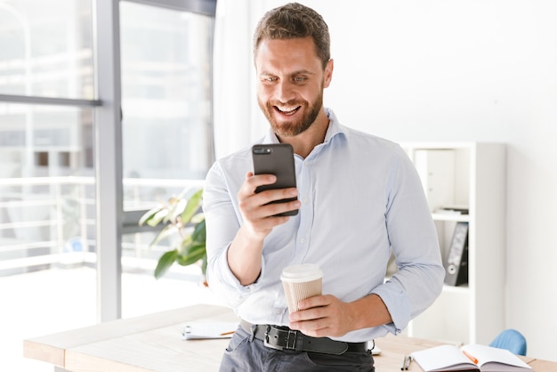 Hombre de negocios emocionado mediante teléfono móvil