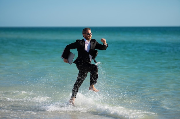 Hombre de negocios emocionado en traje de neopreno correr en el mar hombre de negocios divertido concepto de negocio cómico loco remoto en