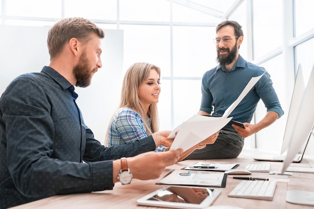 Hombre de negocios y empleados sonrientes que controlan el informe financiero. el concepto de trabajo en equipo