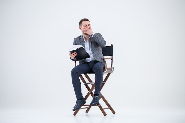 Foto hombre de negocios empresario en un traje sentado en una silla de madera y lanza documentos. sobre un fondo blanco con pensamientos de un nuevo proyecto