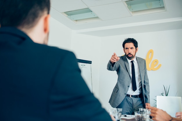 Foto hombre de negocios enfadado señalando a su empleado