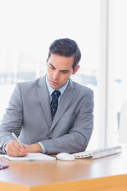 Hombre de negocios enfocado escribiendo en su escritorio