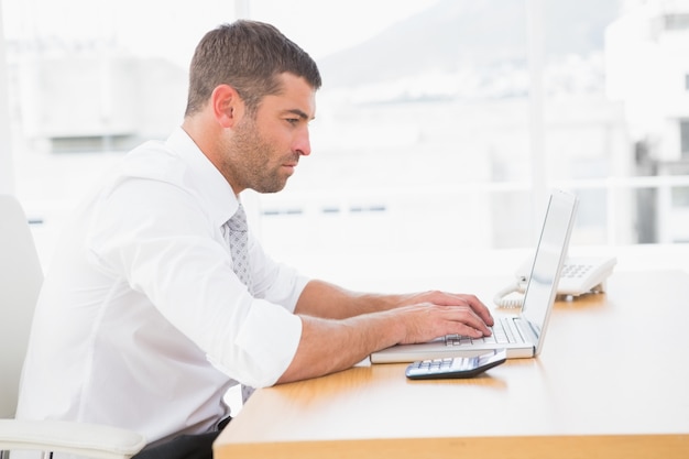 Hombre de negocios enfocado que trabaja en su computadora portátil