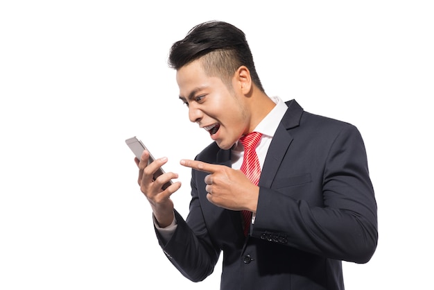 Hombre de negocios enojado gritando en el teléfono inteligente, de pie sobre fondo blanco.