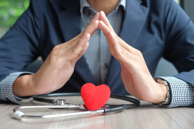 El hombre de negocios entrega el corazón y el estetoscopio. Cuidado de la salud y seguro