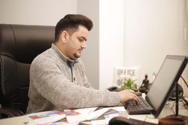 Foto un hombre de negocios está escribiendo algo en la computadora al ver el periódico.