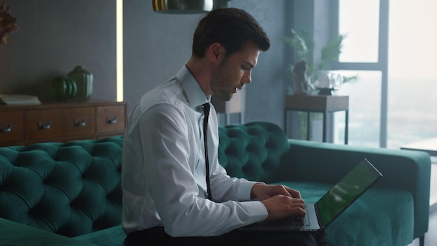 Hombre de negocios escribiendo en la computadora portátil con pantalla verde en la oficina