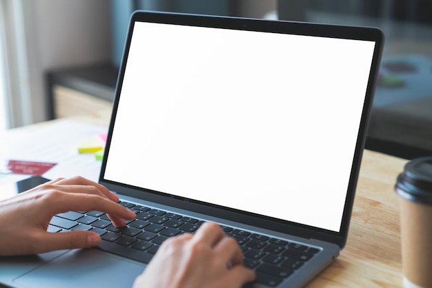 Hombre de negocios escribiendo a mano en su portátil y trabajando en la computadora en una maqueta en blanco de pantalla de mesa de madera