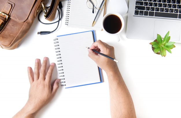 Hombre de negocios escribir en el cuaderno en blanco. Mesa de escritorio de oficina blanca