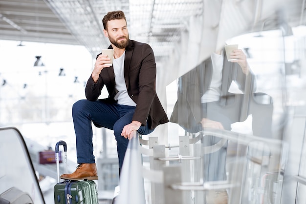 Hombre de negocios esperando con café para ir al aeropuerto. Concepto de viajes de negocios