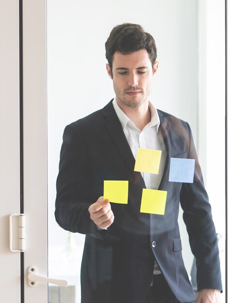 El hombre de negocios está escribiendo la idea para fijarlo ventanas para el plan