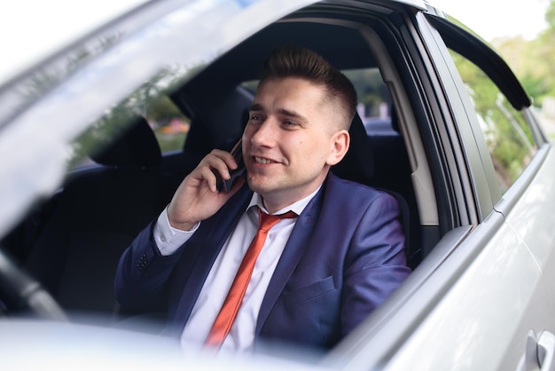 Un hombre de negocios está hablando por teléfono en un coche.