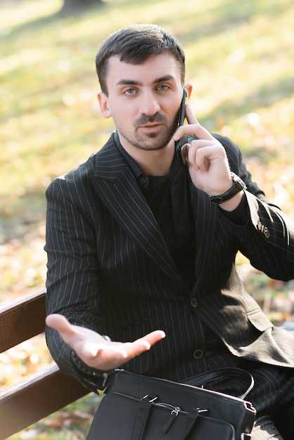 El hombre de negocios está hablando por teléfono mostrando el gesto de la mano Foto de alta calidad