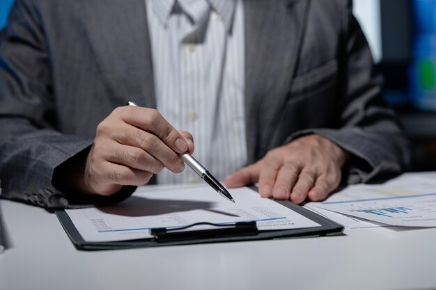 Un hombre de negocios está sentado y trabajando en su oficina en una empresa Un empleado está escribiendo información en un informe para presentarlo a su supervisor en la reunión del día siguiente