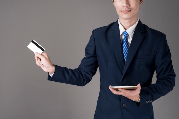 El hombre de negocios está sosteniendo la tarjeta de crédito y la tableta, haciendo compras en línea concepto