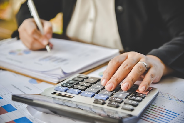 El hombre de negocios está trabajando con una calculadora y un documento.