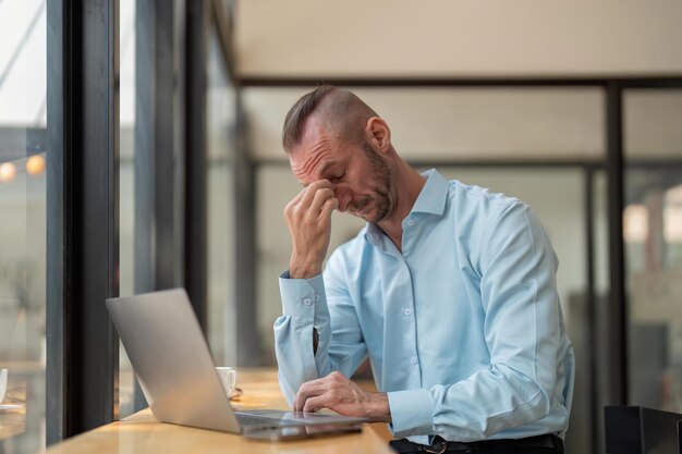 Hombre de negocios estresado sentado en el lugar de trabajo de la oficina Hombre de oficina cansado y sobrecargado de trabajo Hombres jóvenes agotados en estrés trabajando en una computadora portátil