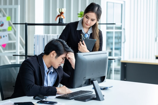 Hombre de negocios estresado en el trabajo con socios de negocios que ayudan a recomendaciones positivas y se animan mutuamente a trabajar con ideas de computadora en una reunión en el fondo de la oficina.