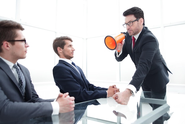 Foto hombre de negocios estricto con un megáfono en una reunión con empleados la metáfora empresarial