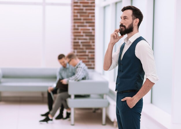 hombre de negocios exitoso hablando por teléfono inteligente en la oficina.