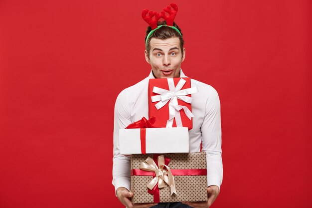 Hombre de negocios feliz caucásico hermoso que sostiene muchos regalos con el sombrero de santa del desgaste que presenta en fondo aislado blanco.