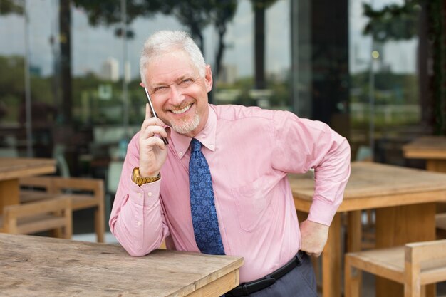 Hombre de negocios feliz hablando por teléfono en el café