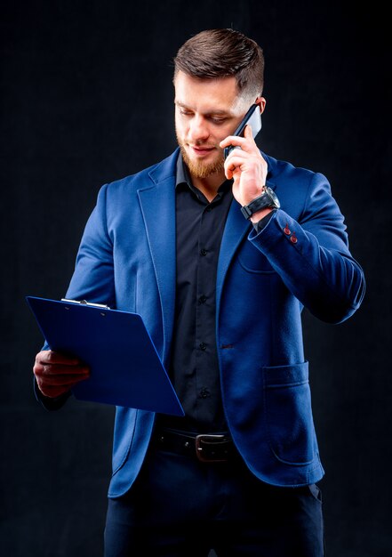 Hombre de negocios feliz hablando por teléfono con la carpeta en la mano