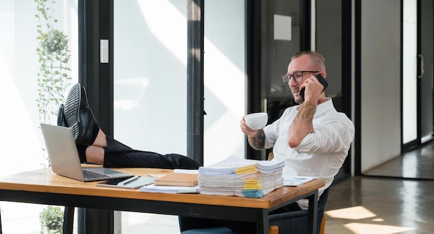 Hombre de negocios feliz con llamada telefónica mientras se relaja en la oficina