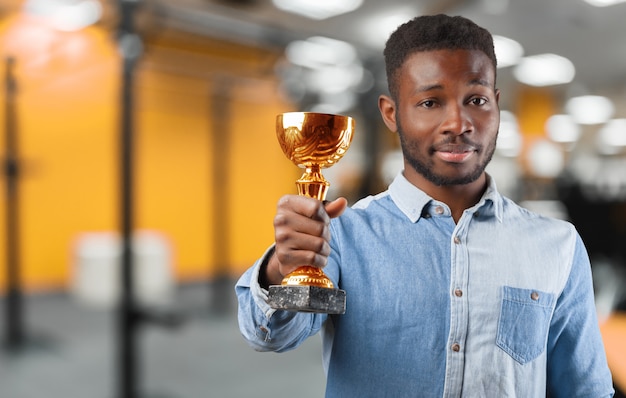 Hombre de negocios feliz negro sosteniendo un trofeo